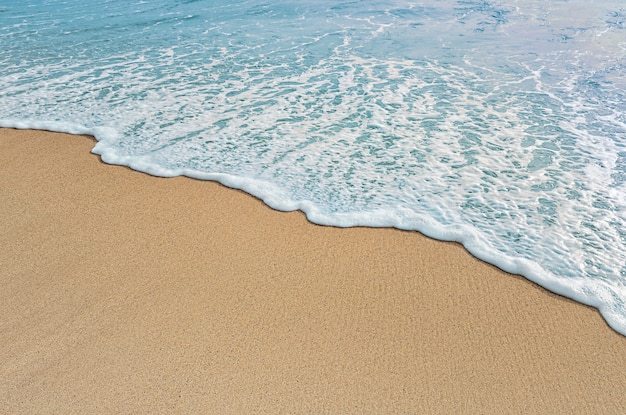 Zachte golf van blauwe oceaan aan zandstrand. Lege plek voor tekst, kopieer ruimte.