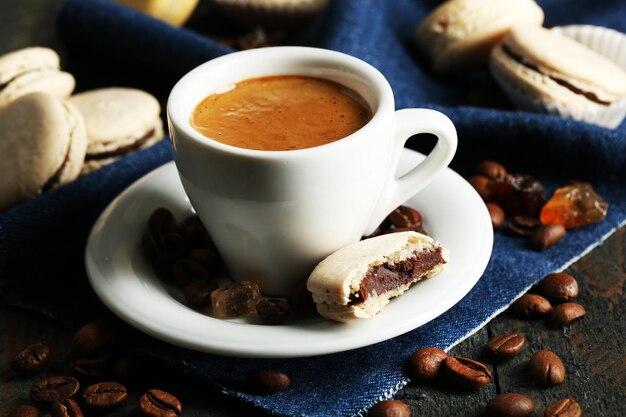 Zachte kleurrijke bitterkoekjes en koffie in mok op houten tafel achtergrond