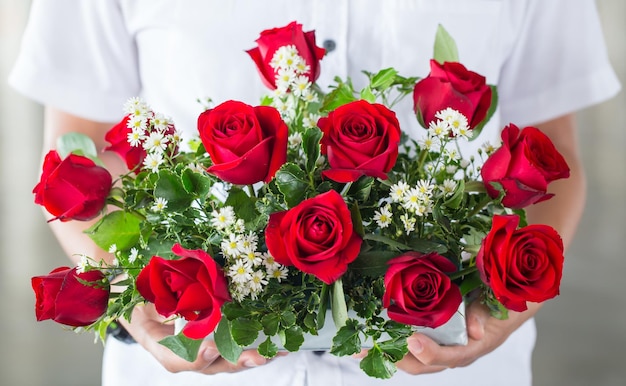 zachte lichte toon met mannelijke hand die een boeket rode rozen geeft