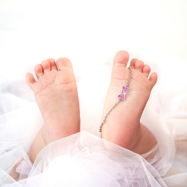 Zachte pasgeboren babyvoetjes en witgouden armband