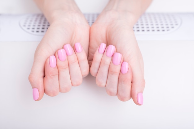 Zachte roze manicure. vrouwelijke handen in manicure salon