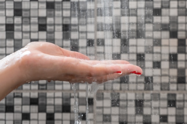 Zachte selectieve aandacht van handen en druppeltjes water uit de douche