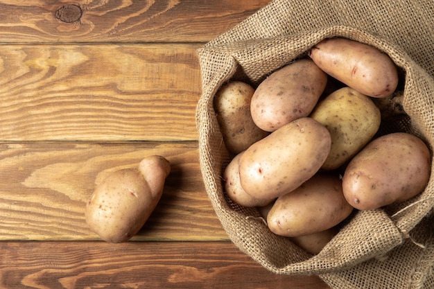 Zak aardappelen na de oogst op vintage houten planken Biologische aardappel om te koken