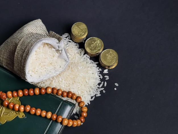 Zakat concept. Selective focus rice in sack with coins,rosary and Koran.