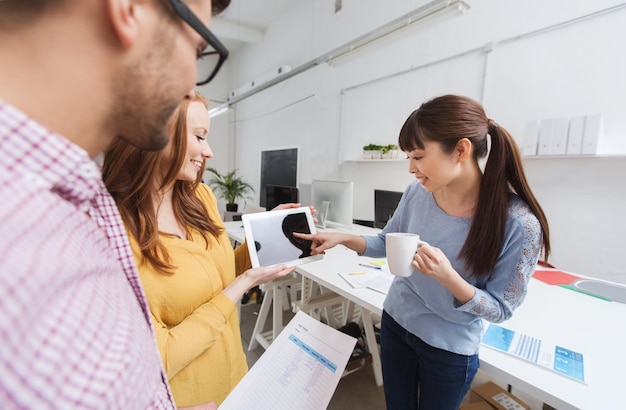 zakelijk, communicatie, opstarten en mensenconcept - gelukkig multiraciaal creatief team of studenten met tablet pc-computer tijdens koffiepauze praten op kantoor