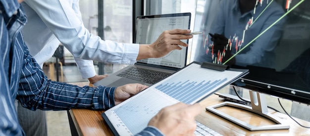 Foto zakelijk handelaarsteam dat de beurs online controleert en grafiekgegevens op het laptopscherm analyseert om te brainstormen over online handelen terwijl u samenwerkt op kantoor