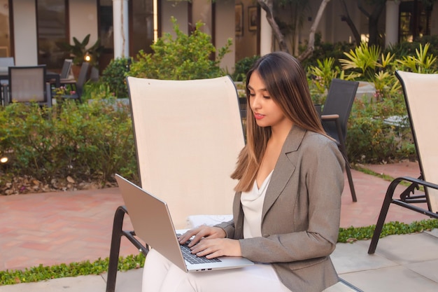 Zakelijk meisje dat met haar laptop op de binnenplaats van een hotel werkt