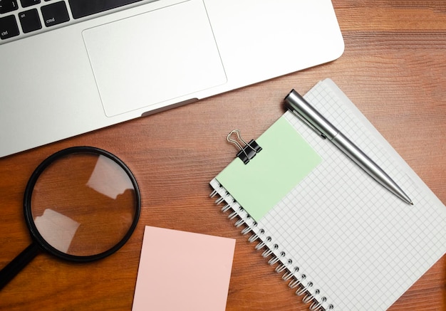 Zakelijk notitieboekje met laptop en vergrootglas aan bureau Hoge kwaliteit foto