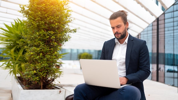 Zakelijk onderweg zakenman werkt op zijn laptop op straat