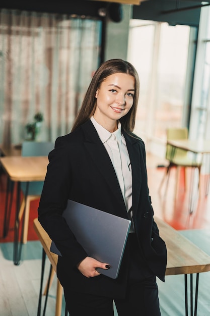 Zakelijk portret van een moderne zakenvrouw met een laptop in het kantoor Zakelijke vrouwen in een zwart klassiek pak