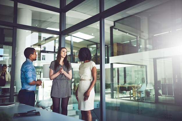 Zakelijk team staat en praat samen op kantoor Ontmoeting en open discussie met collega's op de werkplek Bedrijfsmentor coaching en assisteren van nieuwe werknemers bij het bedrijf