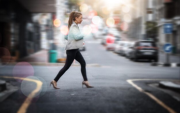 Zakelijk wandelen en een vrouw die een straat in de stad oversteekt terwijl ze haast heeft of te laat op haar werk komt Voetganger en reis met een jonge vrouwelijke werknemer op haar woon-werkverkeer in een stedelijke stad voor een kans