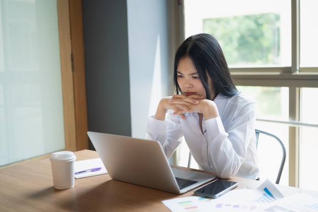 Zakelijke aziatische vrouw voelt zich moe en serieus en werkt met laptop Depressie aziatische vrouw werkt hard