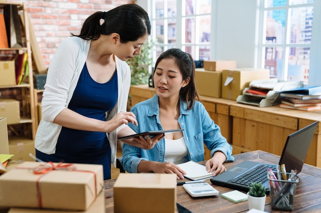 Zakelijke collega met zwangere vrouw die samenwerkt met happy in office. Online marketing verkopers vrouwelijke verpakkingsgoederen bereiden zich voor op levering op tablet. Klein bedrijf en e-commerce concept.