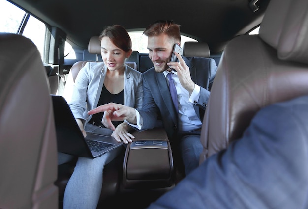 Foto zakelijke collega's gebruiken een laptop om in de auto te werken