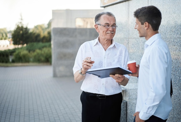 Zakelijke collega's met een digitale tablet die op straat staan tijdens een rookpauze