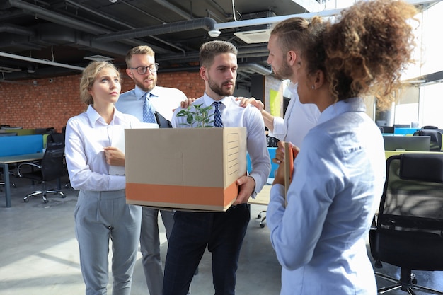 Zakelijke collega's nemen afscheid van de ontslagen werknemer.