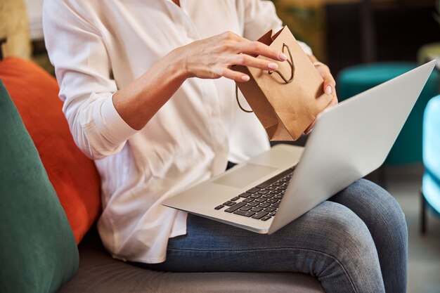 Zakelijke dame met grijze laptop met cadeau in handen