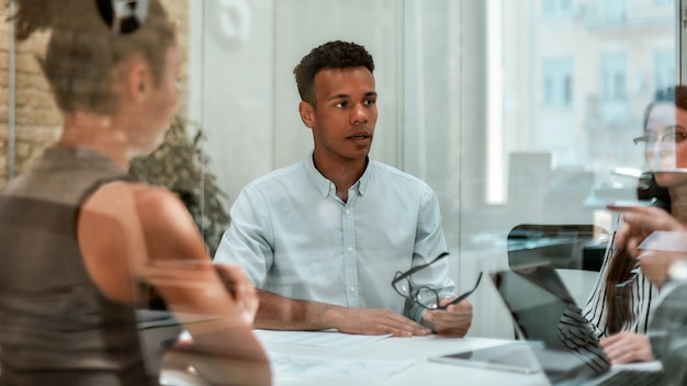 Zakelijke deskundige jonge afro-amerikaanse man die een bril vasthoudt en iets aan zijn uitlegt