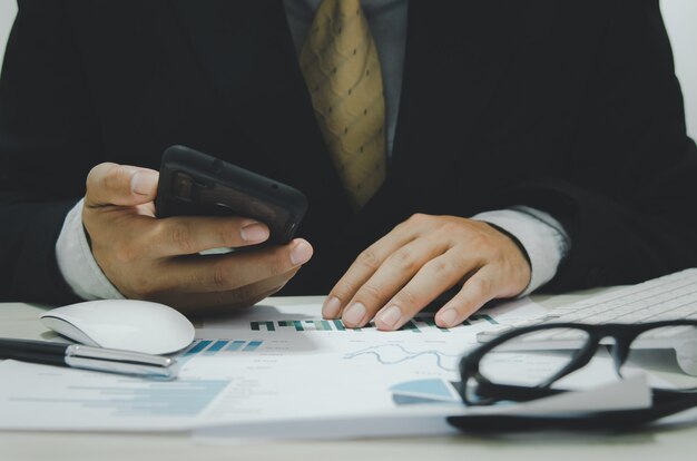 Zakelijke documenten grafieken en grafieken van financiële overzichten en winstgroei met een mobiele telefoon aan het bureau