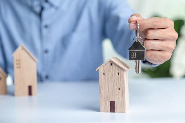 Foto zakelijke hand met huis met koop of huur kopieerruimte vastgoedinvestering en huishypotheek financieel concept hand die geldmuntstapel met houten huis zet