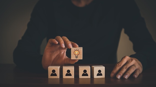 Zakelijke ideeën van creativiteit en innovatie Met de hand geplukt houten kubusblok met het nieuwe concept van het gloeilampenpictogram boven houten blok met het pictogram van het collegasymbool dat groepswerk vertegenwoordigt