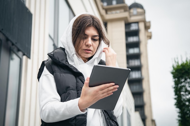 Zakelijke jonge vrouw met een tablet op de achtergrond van het gebouw