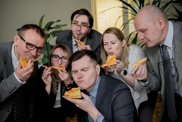 Foto zakelijke lunch en mensenconcept - gelukkig zakelijk team dat pizza eet op kantoor