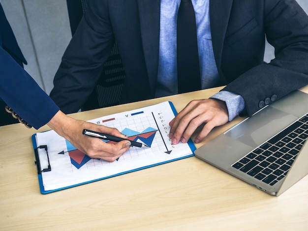 Zakelijke man en vrouw handen controleren rapport grafiek en notebook computer op Bureau, vergadering en samen te werken in kantoor.