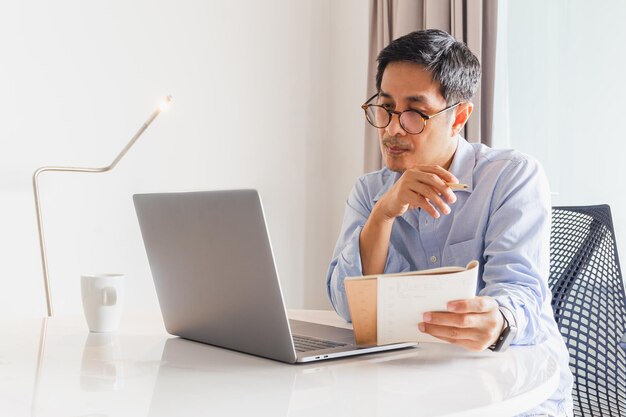 Zakelijke man werkende laptop met pen en notitieboekje in zijn hand