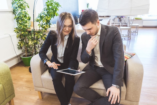 Zakelijke meid en jongen kijken naar tablet, op kantoor