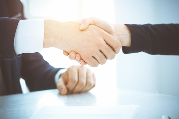 Zakelijke mensen die handen schudden en een vergadering of onderhandeling afronden in een zonnig kantoor. Zakelijke handdruk en partnerschap concepten.
