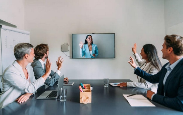 Zakelijke mensen kijken naar een scherm en zwaaien tijdens een online videoconferentie
