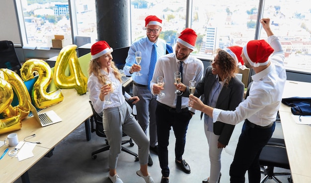 Zakelijke mensen vieren Vrolijk Kerstfeest in een modern kantoor en drinken champagne.