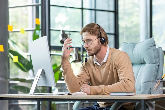 Zakelijke online ontmoeting met een serieuze jonge man, een zakenman, een programmeur zit op kantoor in een