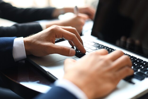 Zakelijke partners werken samen aan een bureau, ze gebruiken een laptop.