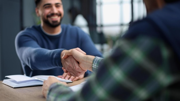 Zakelijke partnerschapsbijeenkomst op kantoor twee zakenlieden die elkaar de hand schudden terwijl ze aan tafel zitten