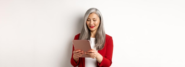Zakelijke succesvolle senior zakenvrouw werken met digitale tablet leesscherm en lachende stan