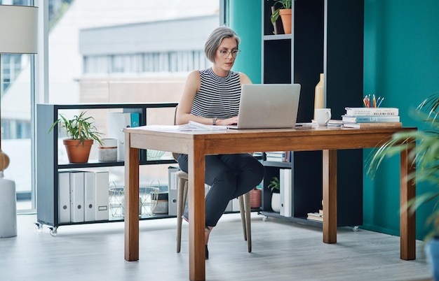 Zakelijke volwassen vrouw en laptop in het kantoor voor financiële planning, loonlijst of boekhouding van het bedrijf, professionele accountant en technologie aan het bureau voor het bijwerken van het begrotingsbeleid en het typen van verkoopvoorstellen