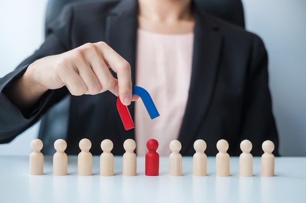 Foto zakelijke vrouw hand met magneet en trekken man houten figuur uit de menigte werknemer business human resource management werving teamwerk strategie giftige mensen en leiderschap concepten