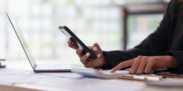 Zakelijke vrouw hand met pen en mobiele telefoon met spaarrekening toepassingsrekening of geld besparen of verzekering concept