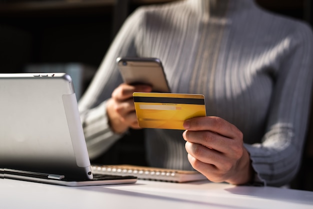 Foto zakelijke vrouw handen met behulp van smartphone en creditcard zitten te houden. online winkelen betalingen concept.