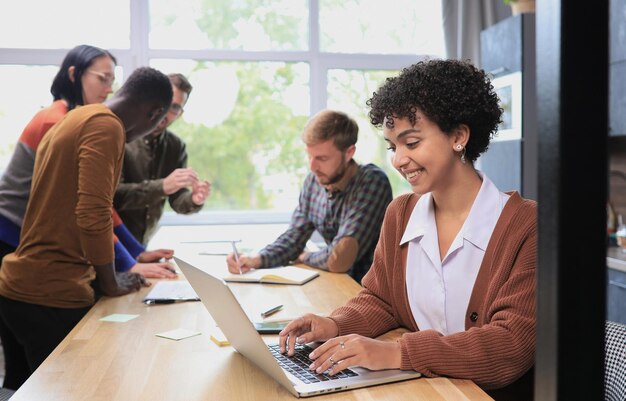 Foto zakelijke vrouw met een laptop in het kantoor met team op de achtergrond