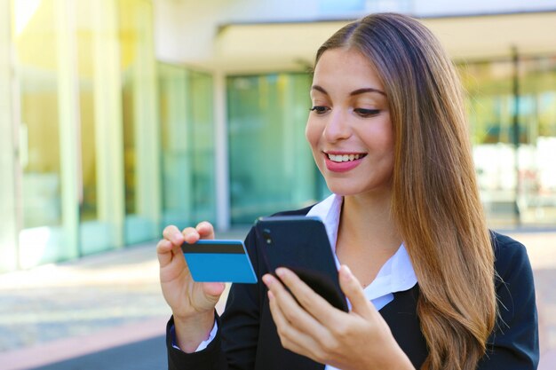 Zakelijke vrouw met telefoon lezen creditcard nummer