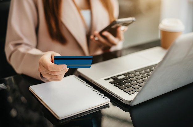 Zakelijke vrouwen gebruiken creditcards om 's ochtends financiële transacties uit te voeren via telefoons, tablet en laptop