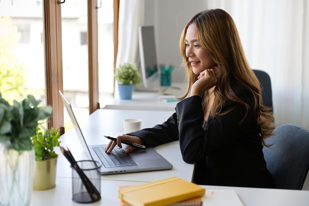 Zakelijke werkneemster of zakenvrouw die op haar draagbare laptopcomputer op kantoor werkt