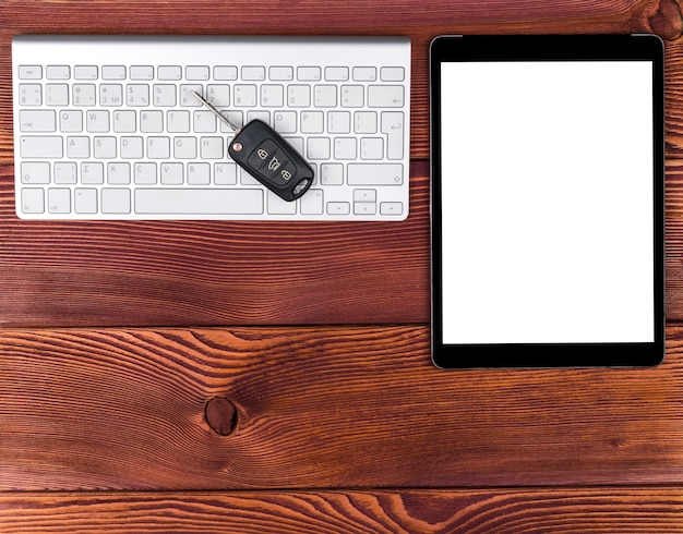 Zakelijke werkplek met draadloos toetsenbord, tabletcomputer en autosleutels op rode houten achtergrond. bureau met kopie ruimte. lege ruimte voor tekst