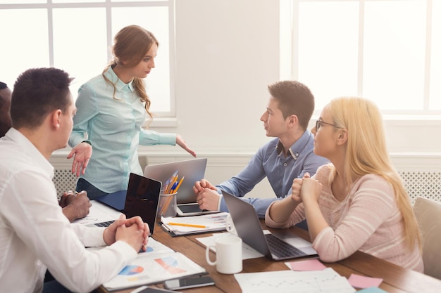 Zakelijke zakelijke bijeenkomst van jong team met vrouwelijke baas. Boze vrouw die tegen haar schuldige arbeiders schreeuwt wegens mislukking. Kantoordiscussie, communicatie met partners, kopieerruimte