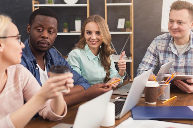 Zakelijke zakelijke bijeenkomst van multi-etnisch team. Jonge vrolijke mensen brainstormen, bespreken nieuw opstartproject op kantoor, kopiëren ruimte