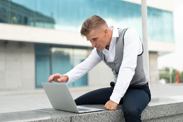 Zakelijke zakenman met behulp van laptop buitenshuis ernstige peinzende blanke man zakenman computer buiten moderne technologie concept jonge volwassen manager crisis denken probleem idee